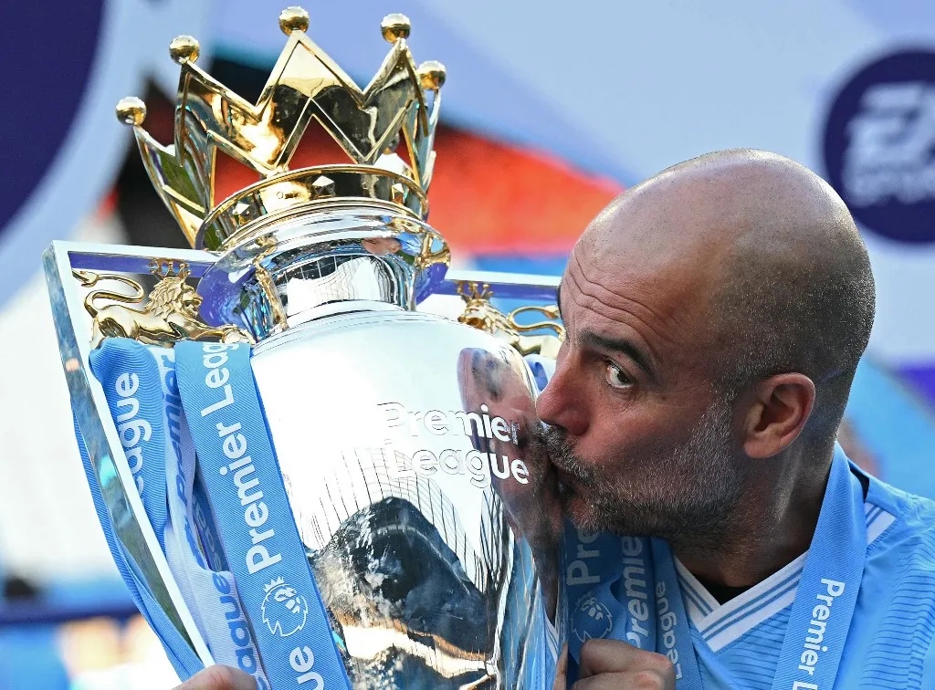(FILES) Manchester City's Spanish manager Pep Guardiola kisses the Premier League trophy after the presentation ceremony following the English Premier League football match between Manchester City and West Ham United at the Etihad Stadium in Manchester, north west England, on May 19, 2024. A press release from the club on May 22, 2026 states: "Manchester City can confirm that Pep Guardiola will step down from his role as Manager this summer." (Photo by Oli SCARFF / AFP) / RESTRICTED TO EDITORIAL USE. No use with unauthorized audio, video, data, fixture lists, club/league logos or 'live' services. Online in-match use limited to 120 images. An additional 40 images may be used in extra time. No video emulation. Social media in-match use limited to 120 images. An additional 40 images may be used in extra time. No use in betting publications, games or single club/league/player publications. / 