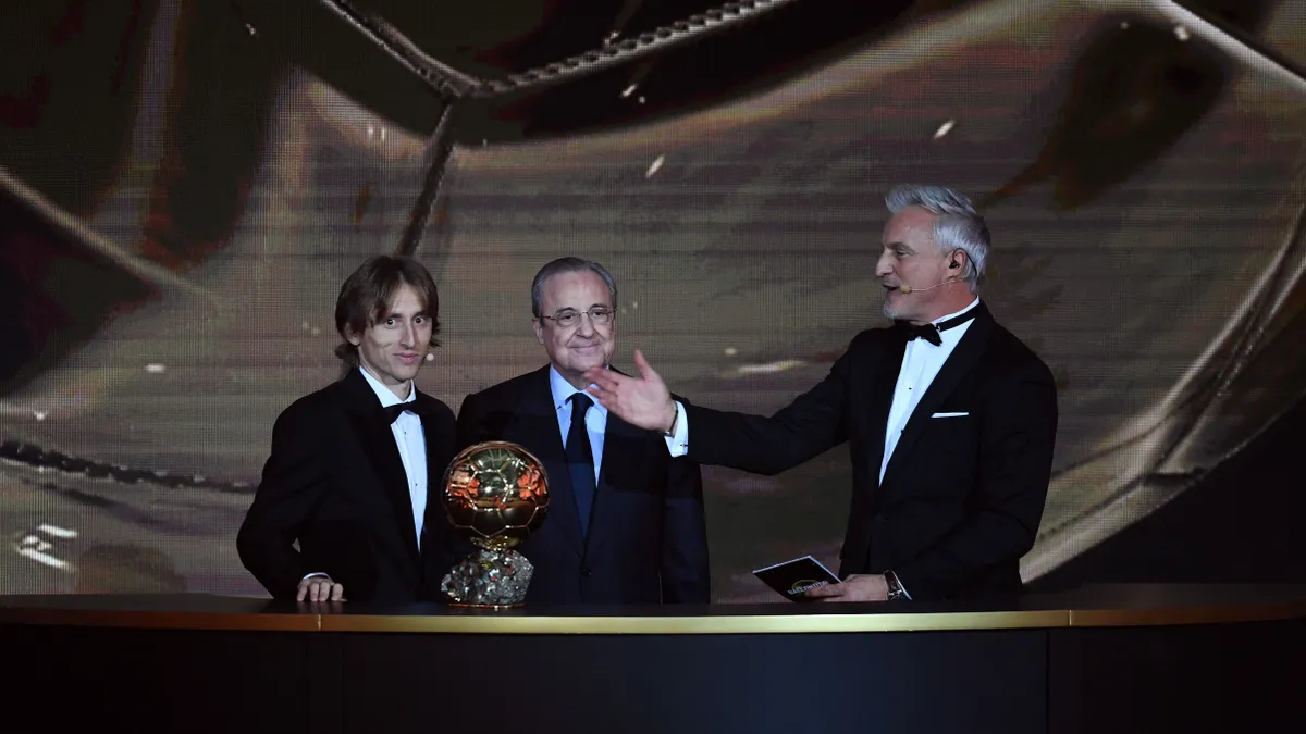Real Madrid's Croatian midfielder Luka Modric (L) is congratulated by Real Madrid's president Florentino Perez (C) and former French footballer and host David Ginola after receiving the 2018 Men's Ballon d'Or award for best player of the year during the 2018 Ballon d'Or awards ceremony at the Grand Palais in Paris on December 3, 2018. (Photo by FRANCK FIFE / AFP)