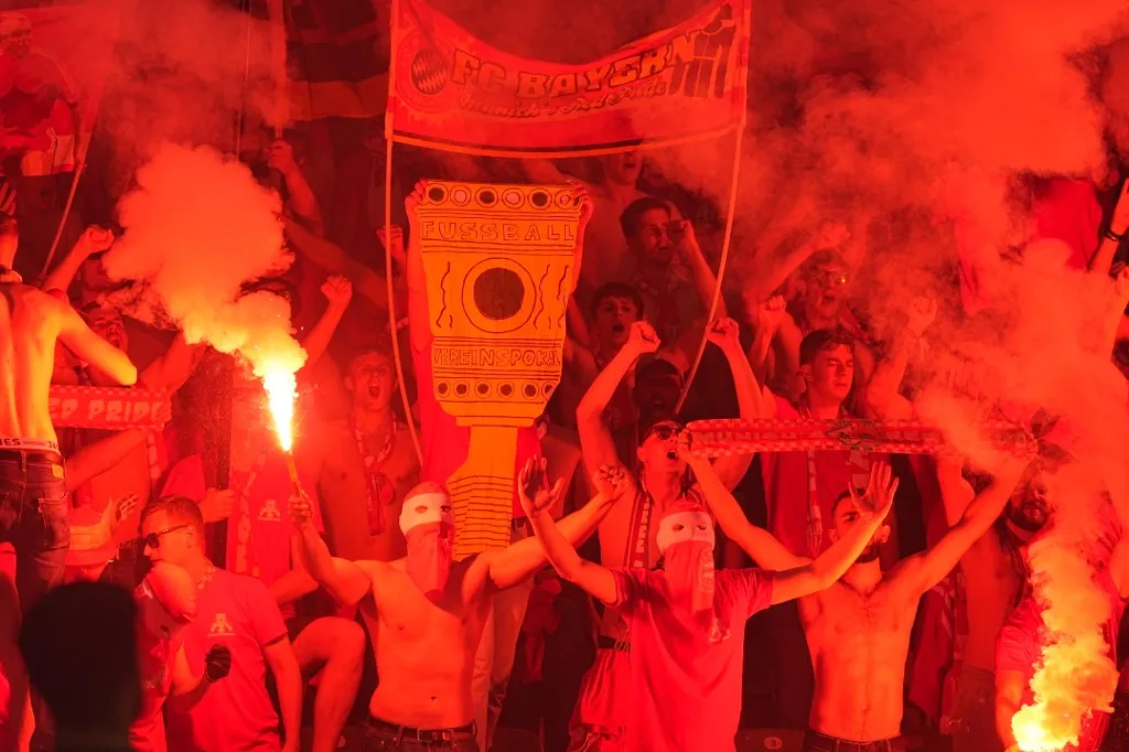 23 May 2026, Berlin: Soccer, men: DFB Cup, FC Bayern Munich - VfB Stuttgart, final in Berlin's Olympic Stadium, Bayern fans set off pyrotechnics and hold up a replica of the DFB Cup. Photo: Michael Kappeler/dpa - IMPORTANT NOTE: In accordance with the regulations of the DFL German Football League and the DFB German Football Association, it is prohibited to utilize or have utilized photographs taken in the stadium and/or of the match in the form of sequential images and/or video-like photo series. (Photo by MICHAEL KAPPELER / dpa Picture-Alliance via AFP)