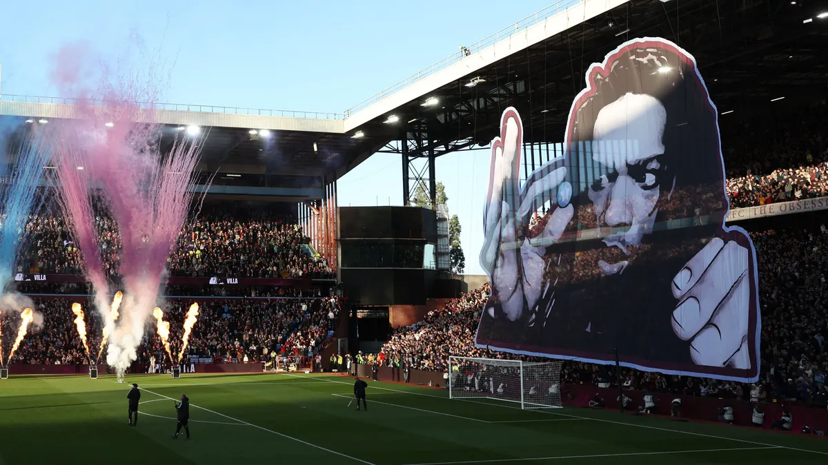Pyrotechnics as the late British poet Benjamin Zephaniah is displayed on a giant tifo ahead of the English Premier League football match between Aston Villa and Liverpool at Villa Park in Birmingham, central England on May 15, 2026. (Photo by Darren Staples / AFP) / RESTRICTED TO EDITORIAL USE. No use with unauthorized audio, video, data, fixture lists, club/league logos or 'live' services. Online in-match use limited to 120 images. An additional 40 images may be used in extra time. No video emulation. Social media in-match use limited to 120 images. An additional 40 images may be used in extra time. No use in betting publications, games or single club/league/player publications. / 