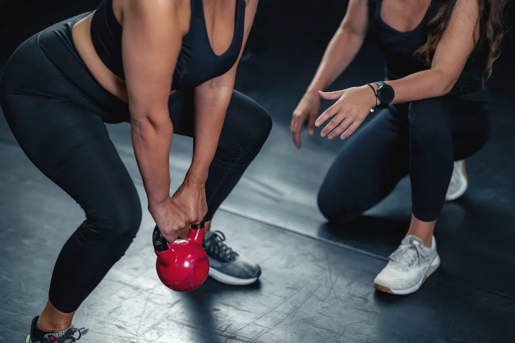 izom Woman doing kettlebell exercise under trainer guidance. (Photo by MICROGEN IMAGES/SCIENCE PHOTO LI / SMD / Science Photo Library via AFP)
