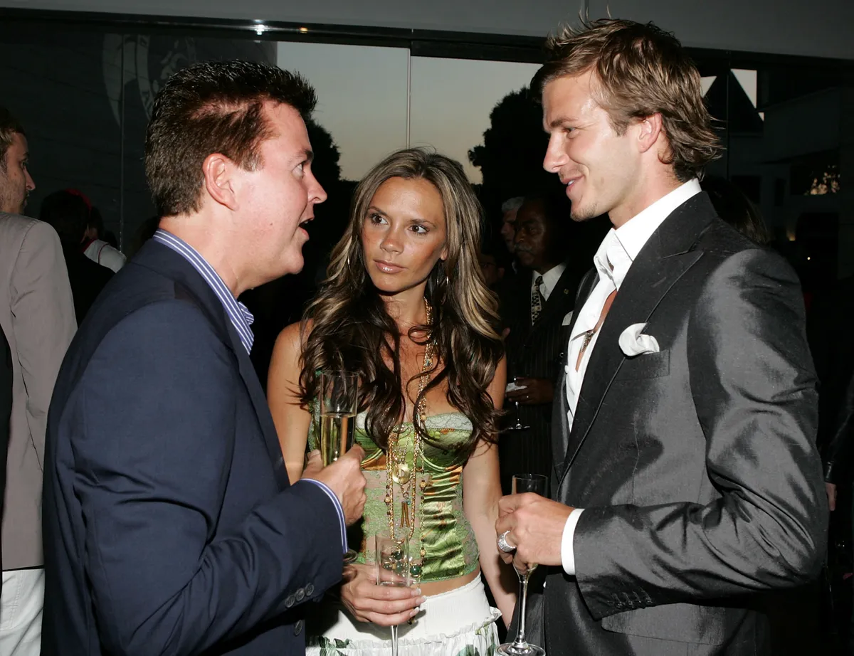 BEVERLY HILLS, CA - JUNE 3:  Creator of "American Idol" Simon Fuller, Victoria Beckham and soccer player David Beckham talk at "The David Beckham Academy" launch party at Creative Artists Agency on June 3, 2005 in Beverly Hills, California. The reception was a celebration in the partnership between sports and entertainment AEG and Beckham, which has established the Los Angeles and London locations of the David Beckham Academy.  (Photo by Frazer Harrison/Getty Images for AEG) *** Local Caption *** Simon Fuller;Victoria Beckham;David Beckham (Photo by Frazer Harrison / Getty Images North America / Getty Images via AFP)