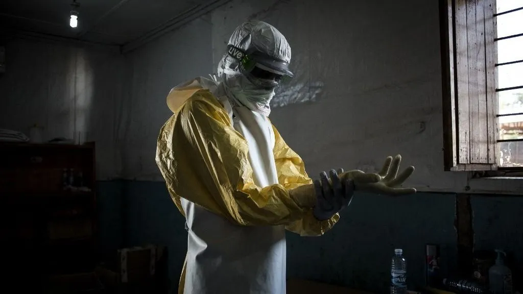 Az ebola tünetei 2–21 napos lappangási idő után is jelentkezhetnek, (FILES) A health worker puts on his personal protective equipment (PPE) before entering the red zone of a MSF (Doctors Without Birders) supported Ebola Treatment Centre (ETC), where he will check up on patients on November 6, 2018 in Bunia, Democratic Republic of the Congo. An outbreak of the ebola virus has been blamed for dozens of deaths in the east of the Democratic Republic of the Congo, African health authorities said on May 15, 2026.The outbreak is in Ituri province. (Photo by John WESSELS / AFP)