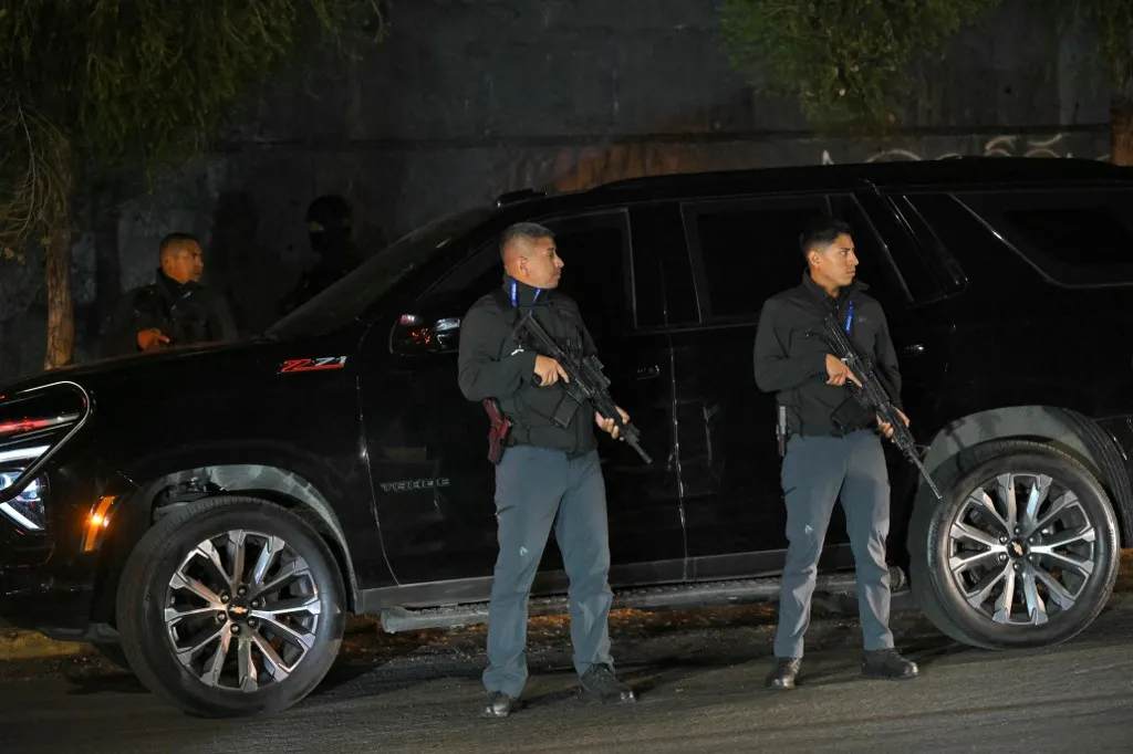 Security personnel guard the vehicle of Ecuador's Interior Minister John Reimberg during a police operation carried out during a curfew imposed by President Daniel Noboa to tackle organized crime, in Quito in the early hours of May 14, 2026. Ecuador's police on May 14 captured a "dangerous" leader of Los Lobos, the country's largest drug trafficking group, in a cinematic operation led by Interior Minister Jhon Reimberg, AFP reporters witnessed. (Photo by AFP)