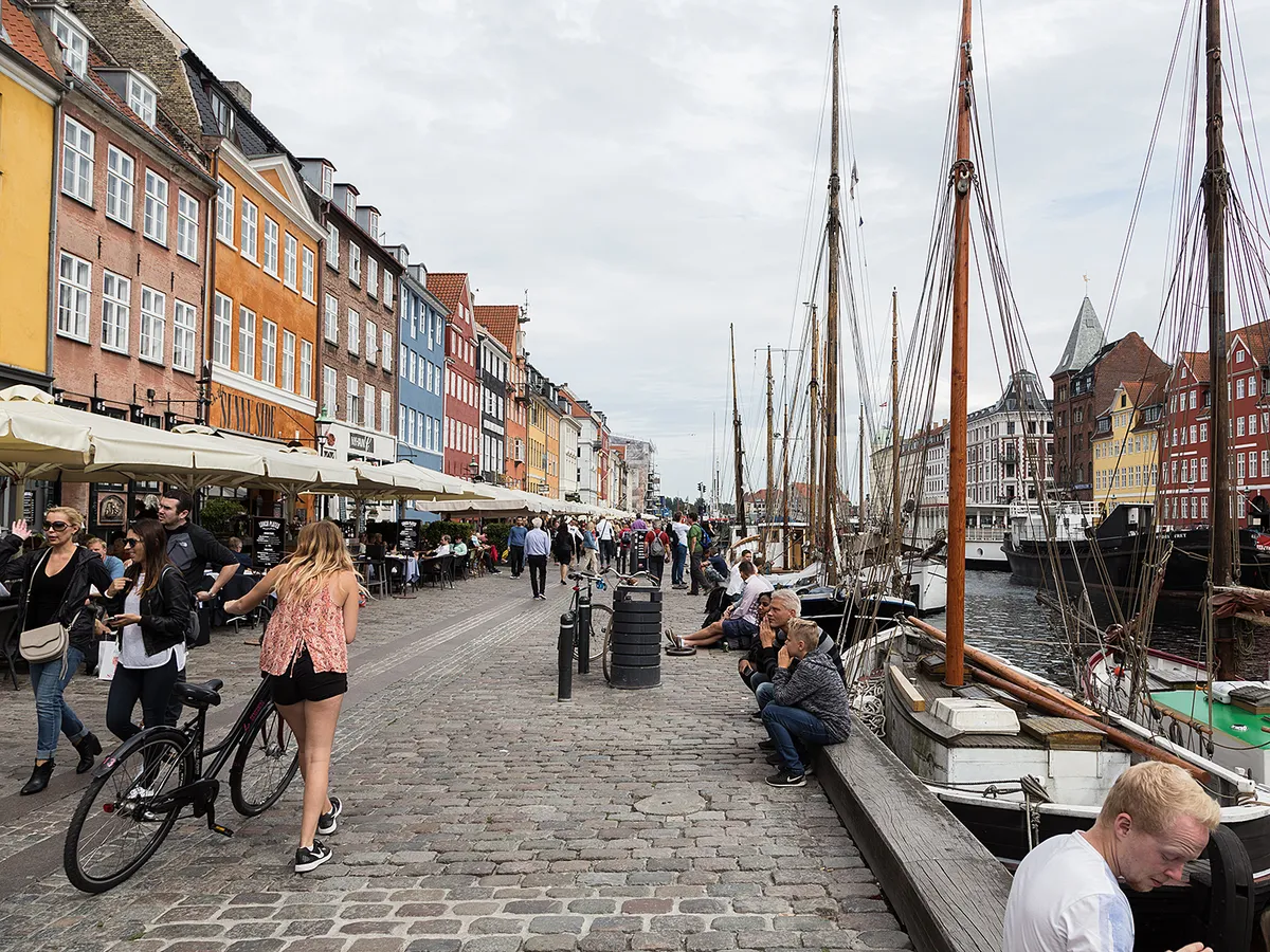 Copenhag, Denmark - July 13, 2016: People walking and cycling with colorful houses around them in Nyhavn,Copenhagen.