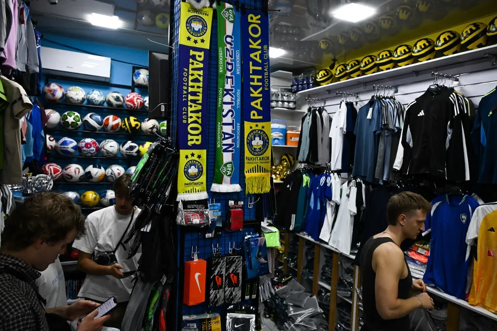 Scarves and football uniforms of the Uzbek national team are seen on sale at a sportswear store near the Pakhtakor stadium in central Tashkent on April 28, 2026. (Photo by Igor IVANKO / AFP)