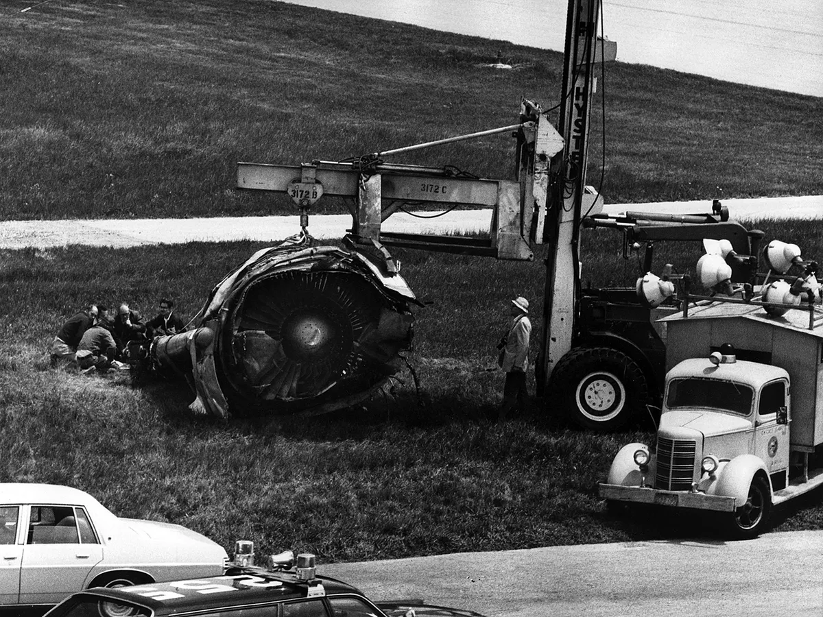 The DC-10 engine lays on the grass just east of Runway 32, right, where it stopped after falling from American Airlines Flight 191, just as the plane rotated from the runway, May 26, 1979. Investigators examine the engine. (Karen Engstrom/Chicago Tribune/Tribune News Service via Getty Images)