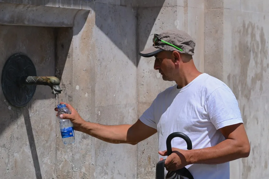 A hőség miatt a következő napokban több helyen 40 Celsius-fok feletti csúcshőmérséklet is előfordulhat (képünk illusztráció) Fotó: ATTILA KISBENEDEK / AFPA tourist fills his plastic bottle with water from a public well during warm weather in Szekesfehervar, Hungary on June 19, 2026. The first major heatwave of the year is on its way, and a Level 2 heat alert will come into force from June 20, according to a statement issued on June 19 by Hungarys National Center for Public Health and Pharmacy (NNGYK) and the National Directorate General for Disaster Management. The particularly hot weather can be especially dangerous for the elderly, children, heart patients, and those with problems of the cardiovascular system. (Photo by Attila KISBENEDEK / AFP)