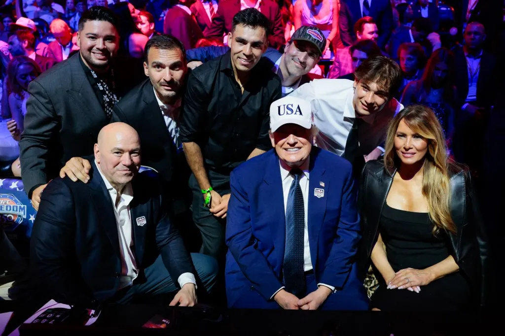 US President Donald Trump smiles as he sits next to US First Lady Melania Trump and UFC CEO Dana White while posing for a photo with other guests during UFC Freedom 250 on the South Lawn of the White House in Washington, DC, on June 15, 2026. (Photo by Evan Vucci / POOL / AFP)