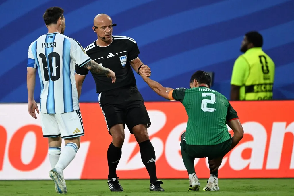Polish referee Szymon Marciniak lifts Algeria's defender #02 Aissa Mandi as he reacts in pain next to Argentina's forward #10 Lionel Messi during the 2026 World Cup Group J football match between Argentina and Algeria at the Kansas City Stadium in Kansas City on June 16, 2026.  (Photo by ROBERTO SCHMIDT / AFP)