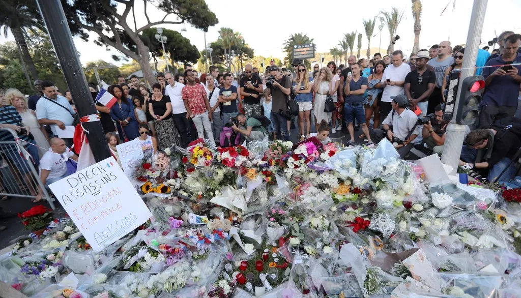 A támadás után sokan gyűltek össze, hogy leróják kegyeletüket az áldozatok előtt, (FILES) People gather around a makeshift memorial to pay tribute to the victims of an attack in the French Riviera city of Nice on July 15, 2016, a day after when a man rammed a truck through a crowd celebrating Bastille Day, killing at least 84 people. Ten years after the attack that killed 86 people and injured more than 400 on July 14, 2016, on Nices Promenade des Anglais, the city is preparing to pay tribute to the victims. (Photo by Valery HACHE / AFP)