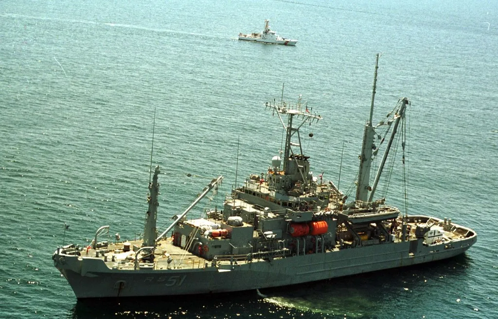 The US Navy salvager USS Grasp sits at anchor off the coast of Martha's Vineyard as the Coast Guard cutter Sanibel (top) patrols a search pattern 20 July 1999 as the search continues for John F. Kennedy Jr.'s airplane which went missing near these waters late 16 July 1999.  AFP PHOTO/POOL/Neal HAMBERG (Photo by NEAL HAMBERG / POOL / AFP)
