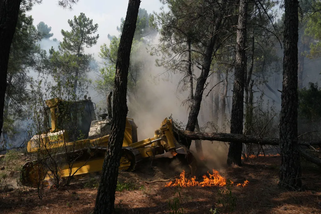 A bulldozer's works to make a firestop in La Atalaya residential area in El Tiemblo, 80 kms west of Madrid, on July 25, 2026 amid wildfires that have burned up to 25,000 hectares. Spanish firefighters hoped to get control of wildfires raging near Madrid o
