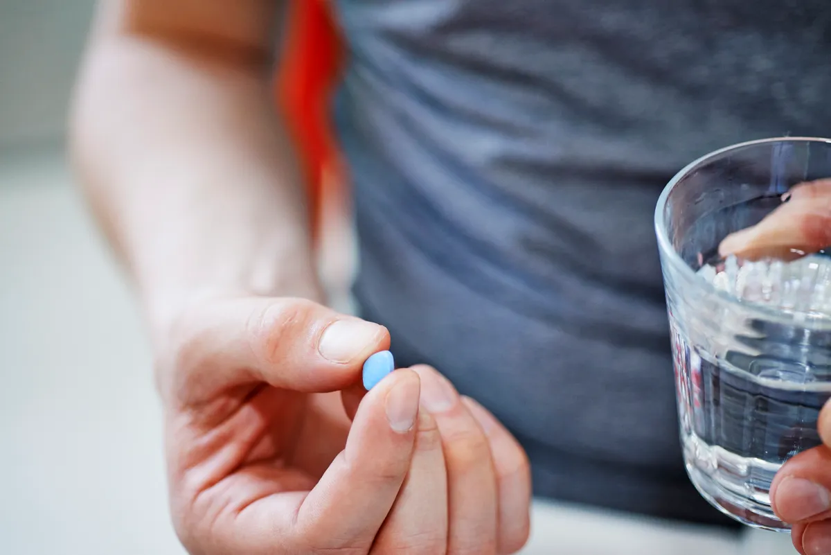 Viagra tablettát tartó ember egy pohár vízzel, a szildenafil lehetséges daganatellenes hatása.
