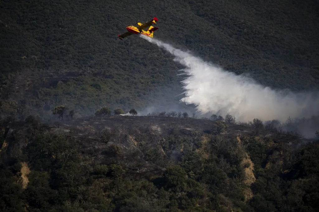 Rekordméretű erdőtüzek pusztítanak Európában, VINCA, FRANCE - JULY 6: Smoke rises as a major wildfire burns out of control in the eastern French Pyrenees near Vinca, France on July 06, 2026. French authorities said the wildfire has burned more than 4,600 hectares, forced the evacuation of around 10,000 people, and injured at least five, including two firefighters seriously. More than 700 firefighters remain on the front lines as strong winds and extreme heat continue to fuel the blaze. The fire has injured at least five people, including two firefighters seriously, while several roads remain closed. French authorities warned that difficult weather conditions are expected to continue in the coming hours. Lorena Sopena Lopez / Anadolu (Photo by Lorena Sopena Lopez / Anadolu via AFP)