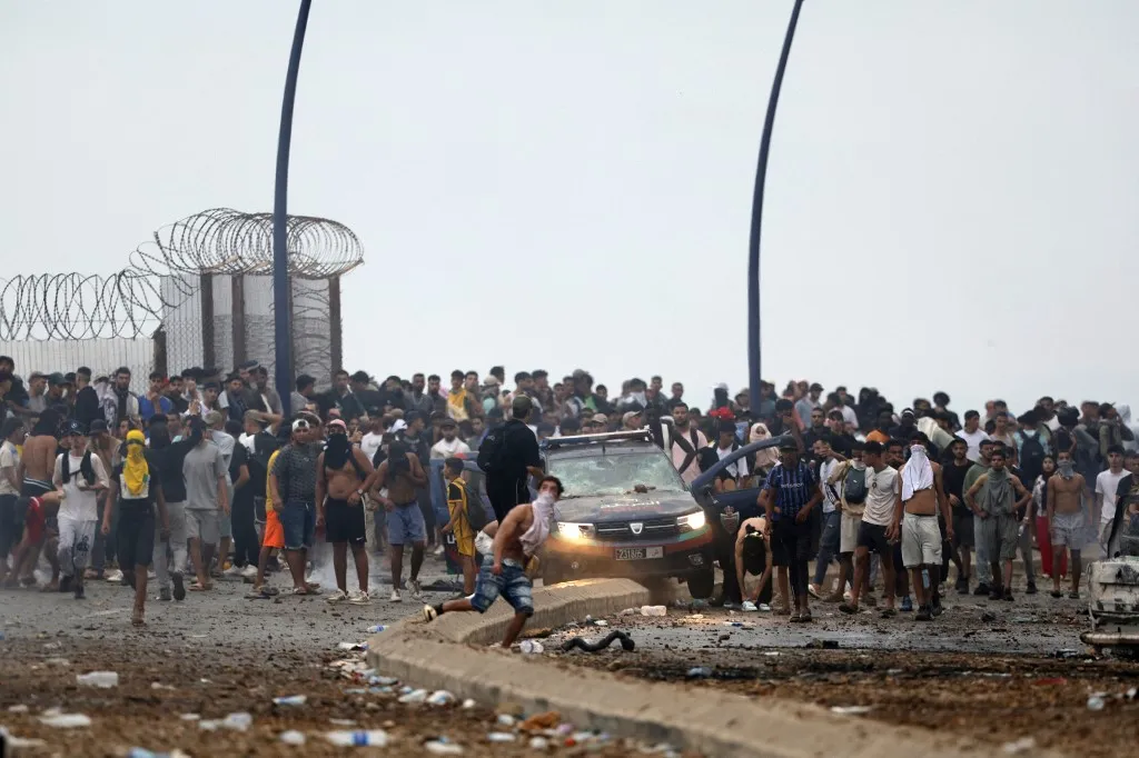 People gather at the site of clashes near Fnideq, on the Morocco-Spain border, on July 31, 2026. Thousands of migrants crossed overnight from Morocco into Spain's north Africa's Ceuta enclave, a police source said on July 31, as Prime Minister Pedro Sanchez was set to arrive to manage the latest migrant crisis on the border. (Photo by Abdel Majid BZIOUAT / AFP)