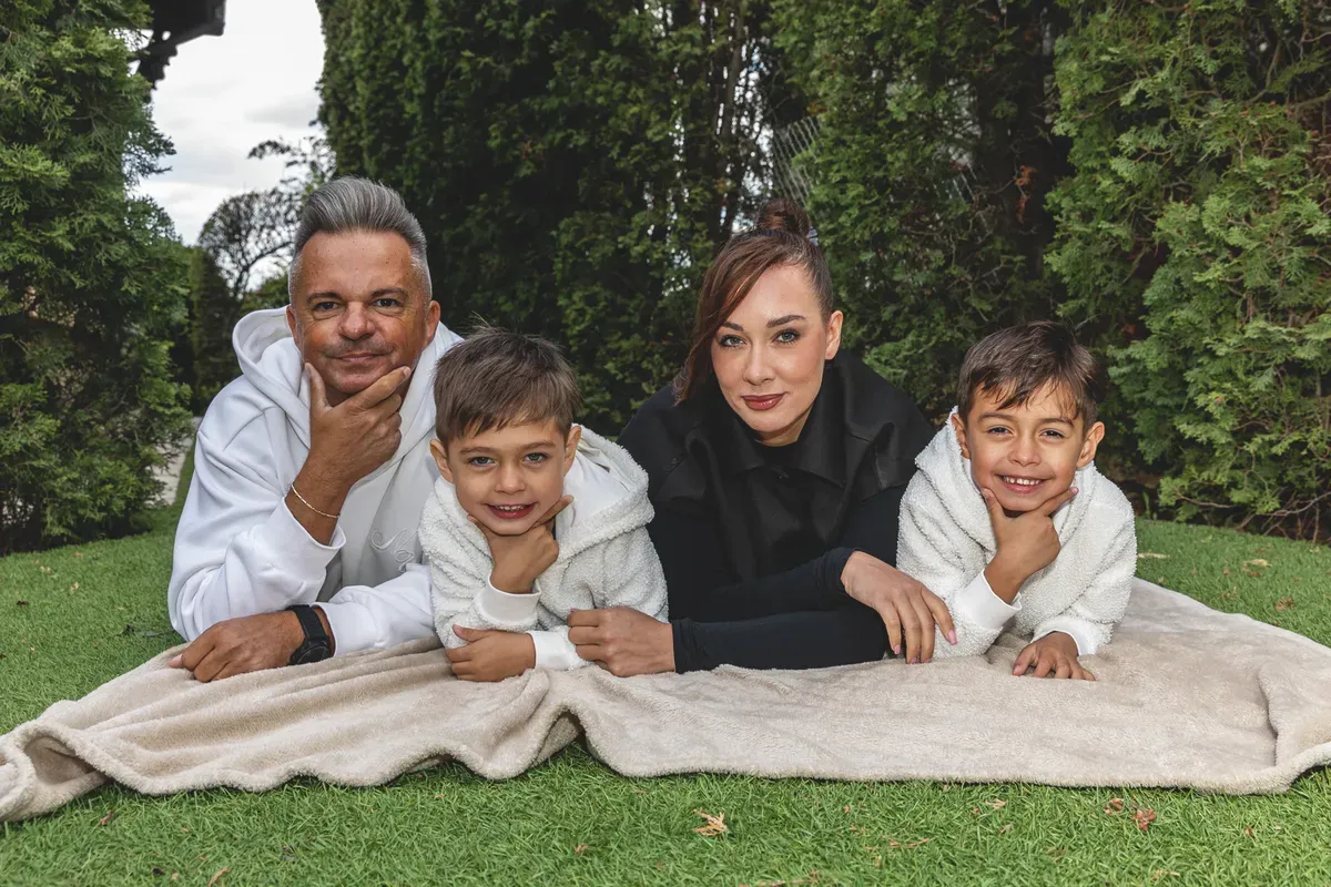 Szécsi Debóra és családja a fűben hasalva mosolyognak a kamerának.