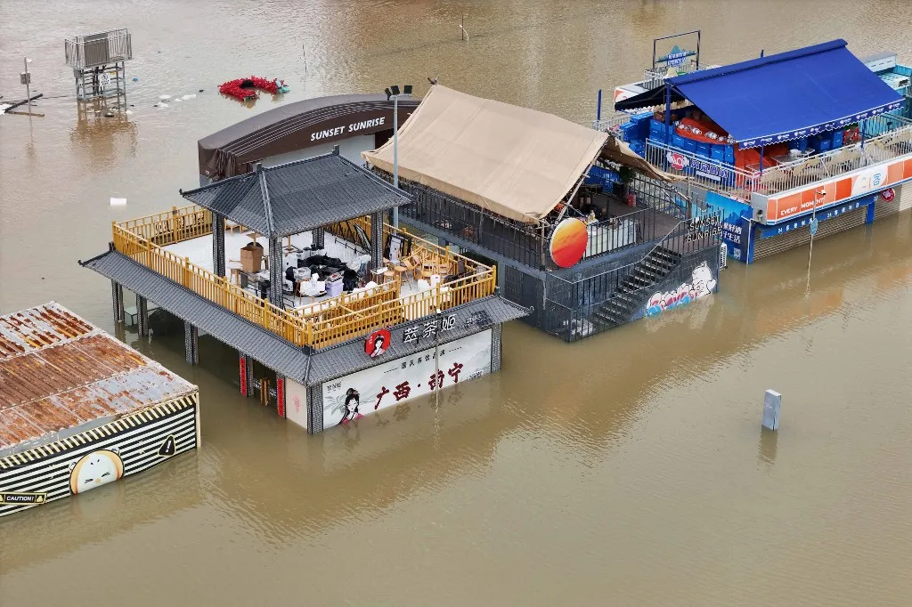 A Maysak tájfun nyomán számos település került víz alá Fotó: - / CN-STR Flooded shops along a submerged riverside walk are seen by the overflowing Yongjiang river in Nanning, in Chinas southern Guangxi region on July 7, 2026. The death toll from devastating storms in parts of China rose to 15 on July 7, with hundreds more injured and tens of thousands evacuated, state media reported, as President Xi Jinping urged "all out" rescue efforts. (Photo by CN-STR / AFP) / China OUT