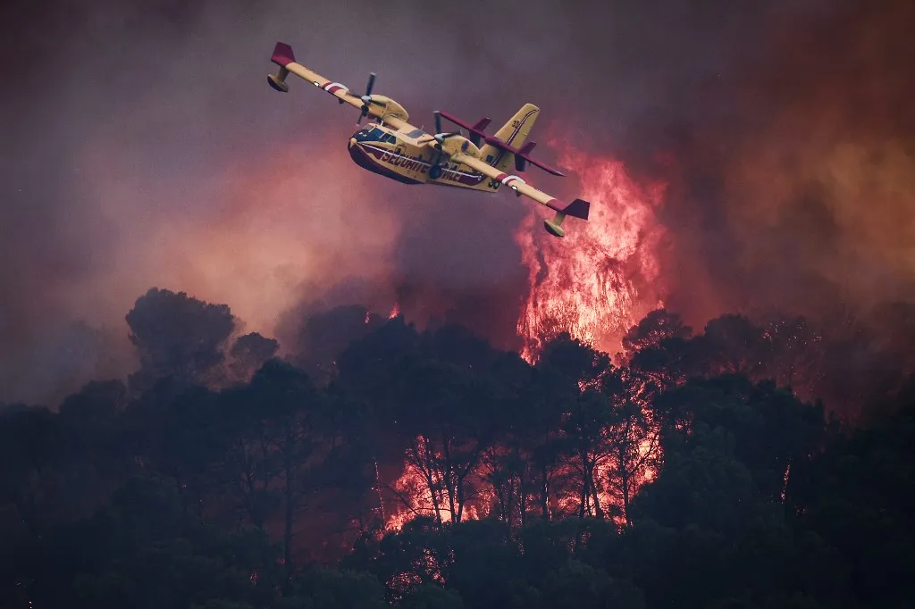 Egy francia polgári védelmi Canadair CL-415 repülőgép repül el a Cotignacot körülvevő erdőtűz felett, Franciaország délkeleti részén.