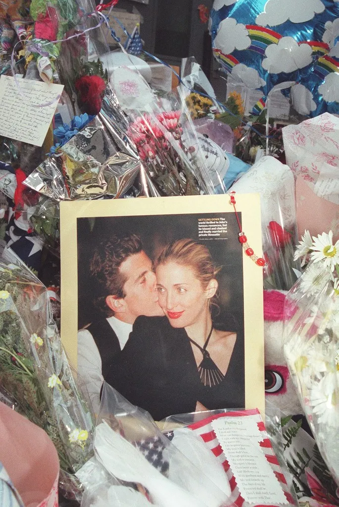 A photo of John F. Kennedy Jr and his wife Carolyn Bessette Kennedy is surrounded by balloons and flowers at a makeshift shrine in front of their apartment building in New York City 21 July 1999. The body of John F. Kennedy, Jr has been located and removed from the wreckage of the small plane he was flying with his wife Carolyn Bessette Kennedy and her sister Lauren G. Bessette on 16 July off the coast of Martha's Vineyard. (Photo by HENNY RAY ABRAMS / AFP)