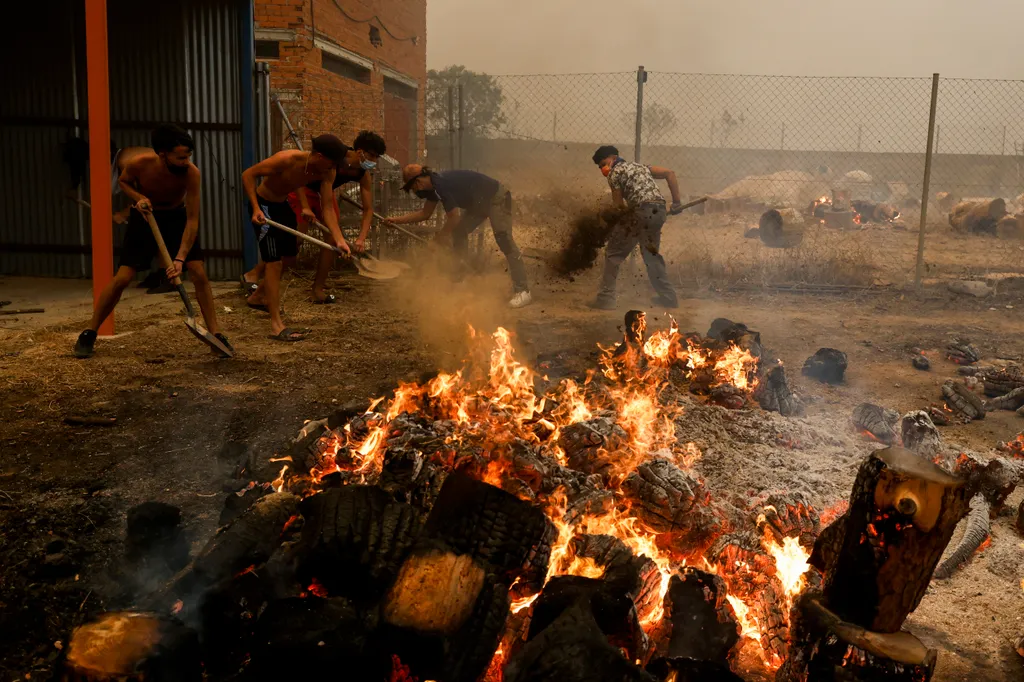EL TIEMBLO, SPAIN - JULY 24: Students of David Gonzalez who owns a Martial Arts gym for young people try to extinguish a fire outside David's house as wildfires surround the village on July 24, 2026 in El Tiemblo, in Ávila province, Spain. The Spanish int