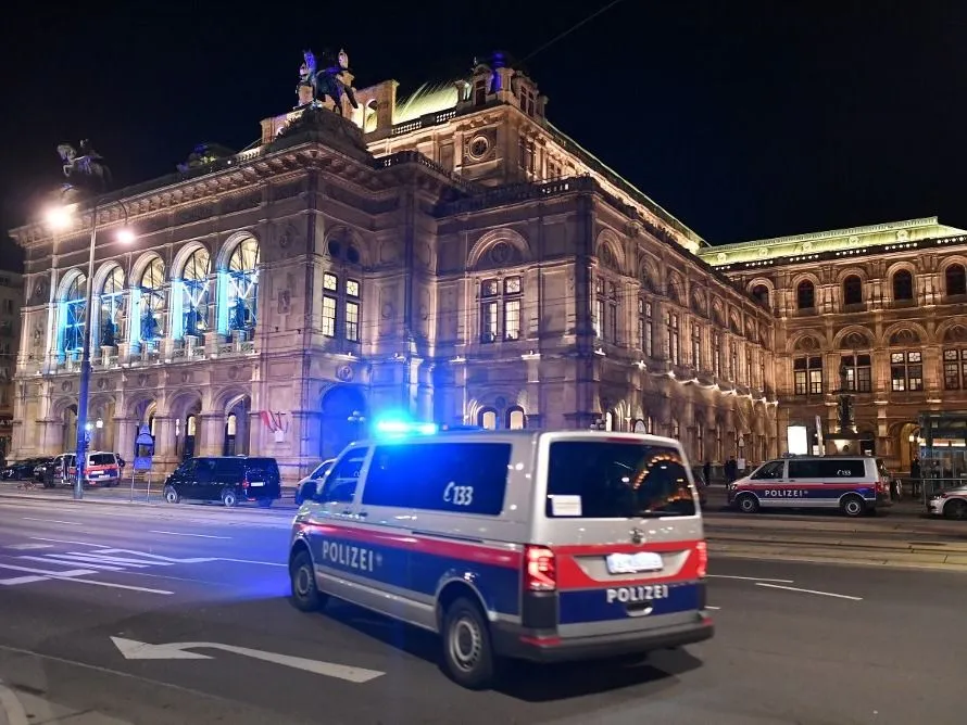 A police car drives in front of the opera house in the center of Vienna on November 2, 2020, following a shooting. Two people, including one attacker, have been killed in a shooting in central Vienna, police said late November 2, 2020. Vienna police said in a Twitter post there had been "six different shooting locations" with "one deceased person" and "several injured", as well as "one suspect shot and killed by police officers". (Photo by JOE KLAMAR / AFP)