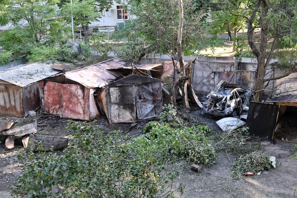 A car destroyed in a drone strike stands near damaged garages in Odesa, Ukraine, on July 6, 2026. The city was targeted with drones, resulting in damage to residential buildings in the Kyivskyi district and a garage cooperative in the Khadzhybeiskyi district. At least one person is injured. (Photo by Nina Liashonok/Ukrinform/NurPhoto) (Photo by Nina Liashonok / NurPhoto via AFP)