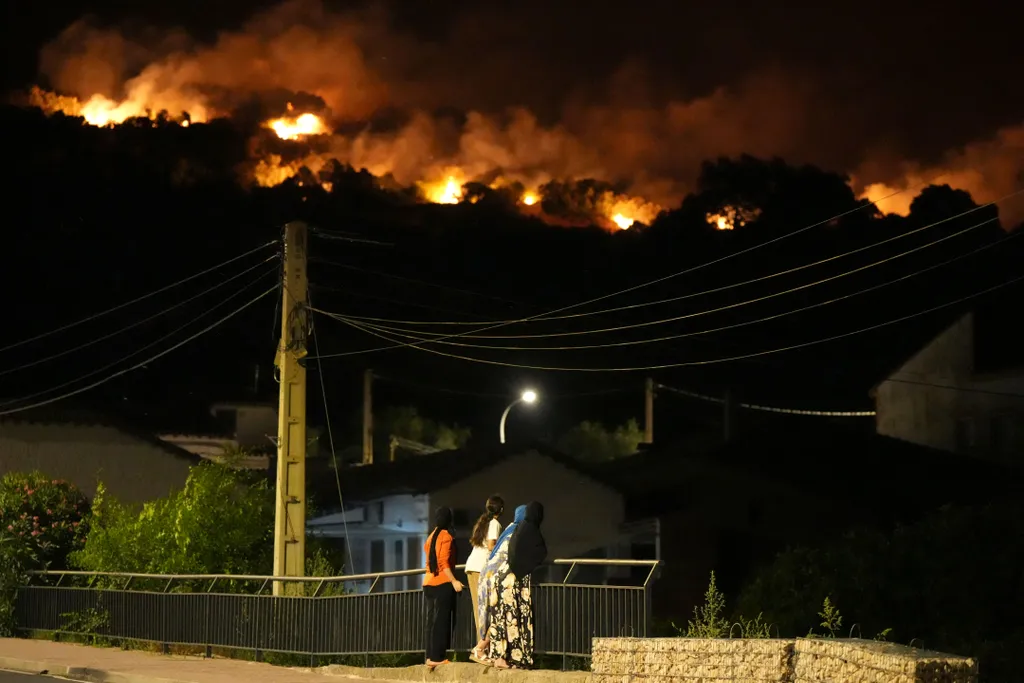Residents watch the flames on hill crests as firefighters battle a wildfire in Cebreros area, near Avila, 80 kms west of Madrid at night on July 24, 2026. The worst wildfires in the Madrid region's history rage west of the Spanish capital, forcing authori