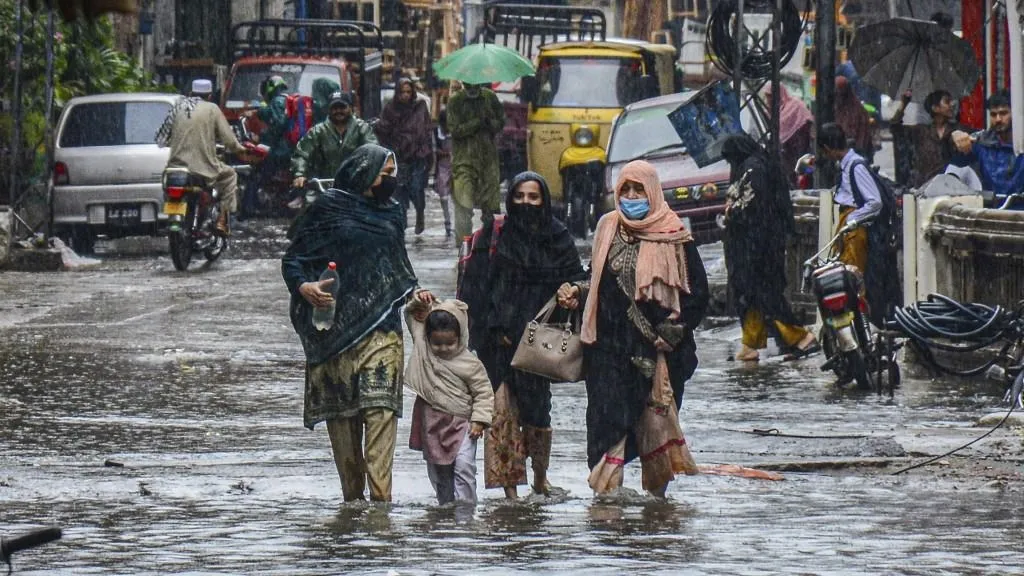 Women and a child walk through a flooded street after heavy rainfall in Rawalpindi, Pakistan, on October 6, 2025. (Photo by Raja Imran / Middle East Images via AFP)