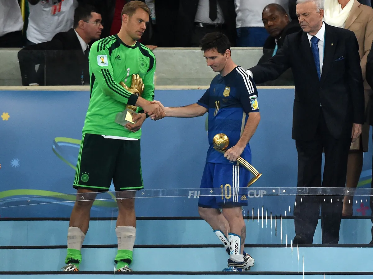 Germany's goalkeeper Manuel Neuer (L) holds his Goldan Glove trophy awarded to the best goalkeeper of the tournament and Argentina's forward and captain Lionel Messi (2L) holds his Golden Ball trophy for the best player of the tournament as they shake hands after Germany won the 2014 FIFA World Cup final football match between Germany and Argentina 1-0 following extra-time at the Maracana Stadium in Rio de Janeiro, Brazil, on July 13, 2014.  AFP PHOTO / PEDRO UGARTE (Photo by PEDRO UGARTE / AFP)