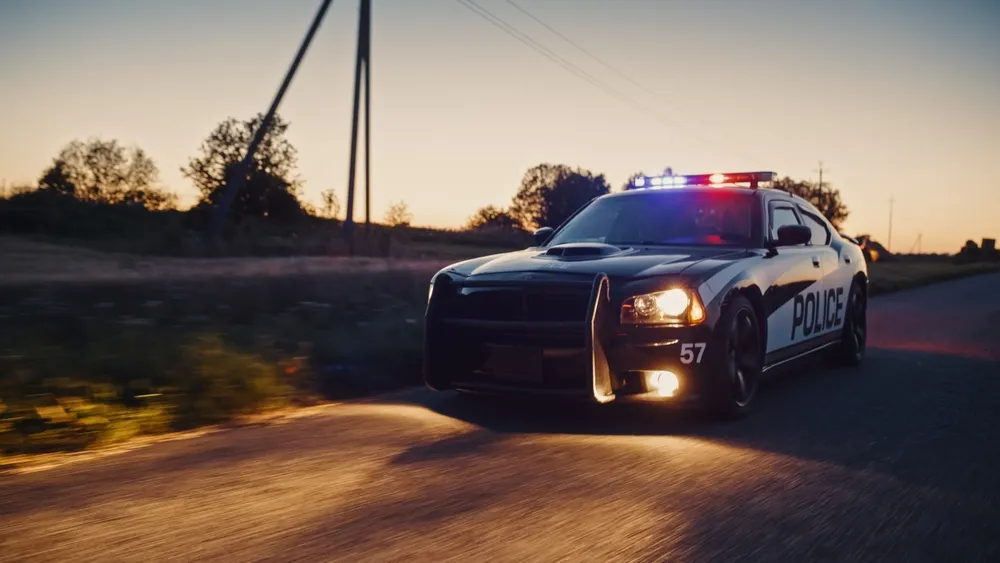 Highway Traffic Patrol Car In Pursuit of Criminal Vehicle. Police Officers in Squad Car Chase Suspect on Industrial Area Road. Cinematic Atmospheric High Speed Action Scene