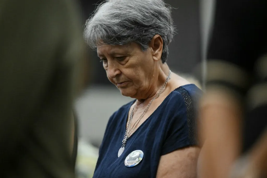 A relative of the Morandi Bridge victims wears a pin displaying her parents in the Courthouse after the verdict in the case of the Morandi Bridge collapse nearly eight years ago that killed 43 people in one of the country's worst infrastructure disasters, in Genoa on July 16, 2026. A Genoa court sentenced a former executive of Italian motorway network Autostrade per l'Italia (ASPI) to 12 years in jail on Thursday for his role in a deadly bridge collapse that killed 43 people in 2018. (Photo by Marco BERTORELLO / AFP)