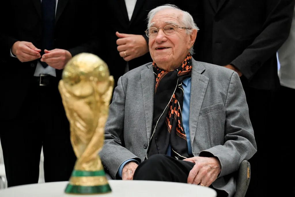 Argentina's sport journalist and football analyst Enrique Macaya Marquez, 91, poses for a photo with a replica of the FIFA World Cup trophy after takin part in a live broadcast on DSports Radio in Munro, Buenos Aires province, Argentina on May 29, 2026. Since Sweden 1958, football has changed in tactical, technological and economic terms. However, one thing has remained constant: the presence of Argentine journalist Enrique Macaya Marquez, who will extend his record of World Cup coverage to 18 in North America 2026. (Photo by Luis ROBAYO / AFP)