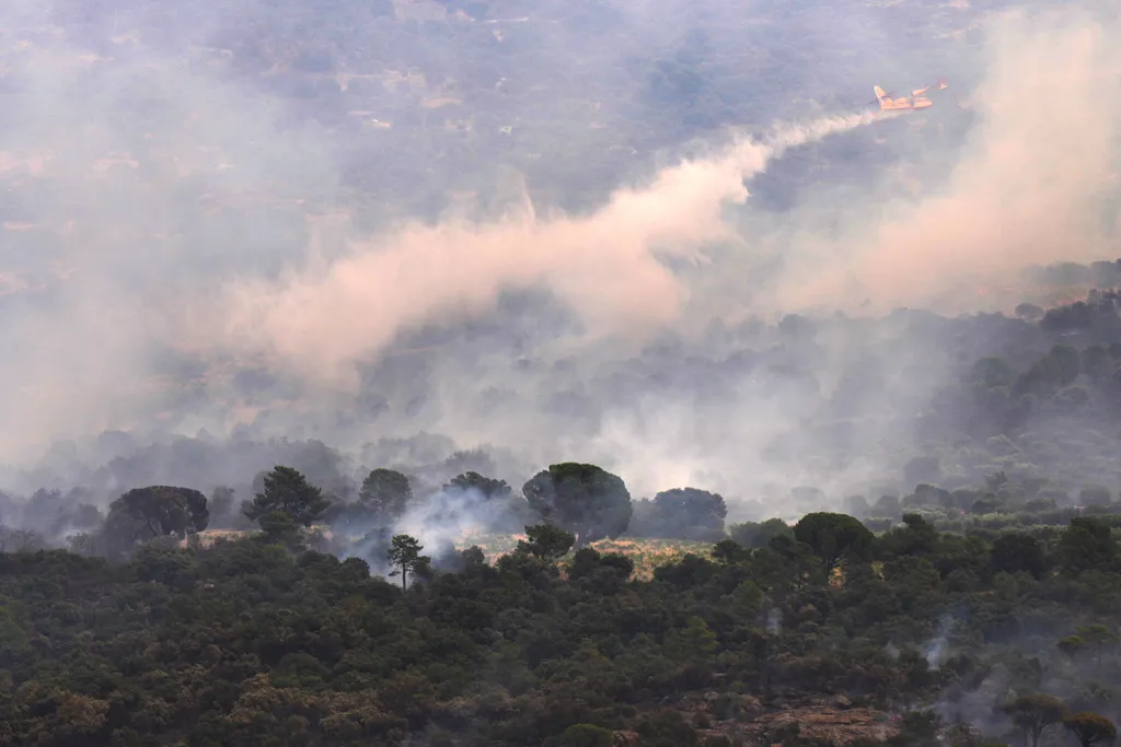 A picture taken on July 25, 2026 from El Tiemblo, 80 kms west of Madrid, shows a plane dumping water to battle wildfire between El Tiemblo and San Martin de Valdeiglesias. Spanish firefighters hoped to get control of wildfires raging near Madrid on Saturd
