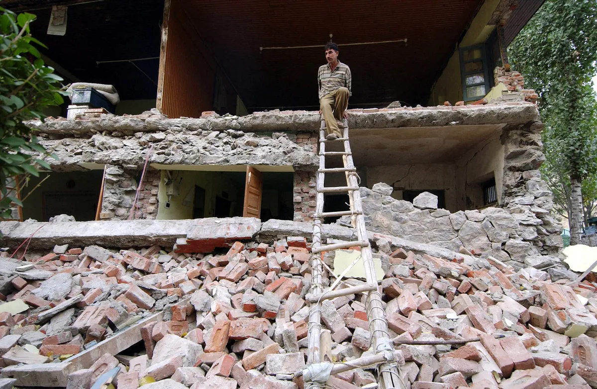 An Indian Kashmiri man uses a ladder to walk down from the first floor of a partially-destroyed police station, following a powerful earthquake measuring at least 7,6 on the Richter scale, in Uri some 100 kms north of Srinagar 08 October 2005. A powerful earthquake measuring at least 7,6 on the Richter scale killed at least 237 people across India's Jammu and Kashmir, a police spokesman said, as the confirmed death toll in the massive earthquake, which rocked India, Pakistan and Afghanistan, has passed 1000, officials said. (Photo by SAJJAD HUSSAIN / AFP)