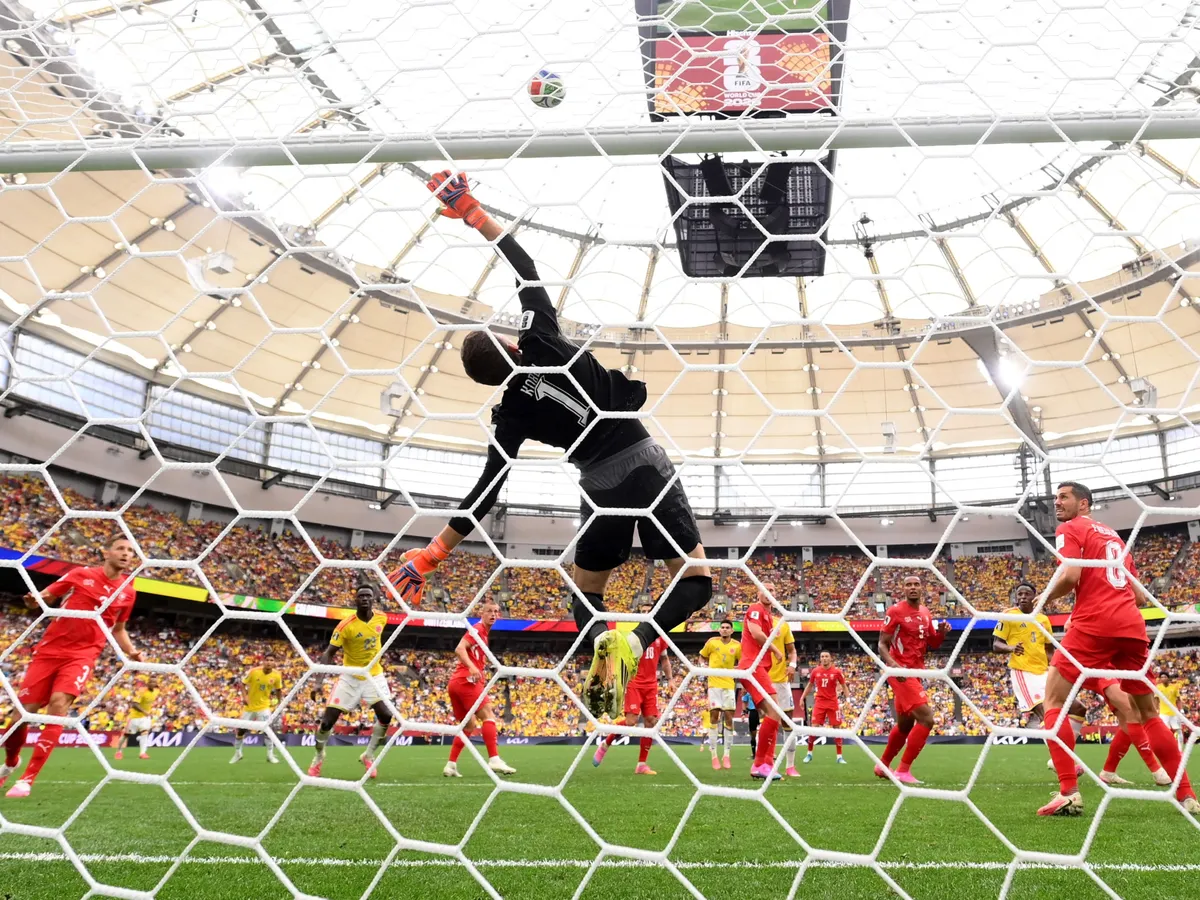 VANCOUVER, CANADA - JULY 07: (EDITOR'S NOTE: Image was captured using a remote camera from behind the goal.) Gregor Kobel #1 of Switzerland dives as the header of Jhon Lucumi #3 of Colombia hits the cross bar during the FIFA World Cup 2026 Round of 16 match between Switzerland and Colombia at BC Place Vancouver on July 07, 2026 in Vancouver, British Columbia, Canada.   David Ramos/Getty Images/AFP (Photo by David Ramos / GETTY IMAGES NORTH AMERICA / Getty Images via AFP)