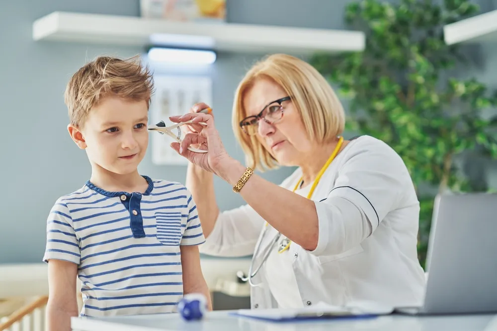Pediatrician doctor examining little kids in clinic ears check