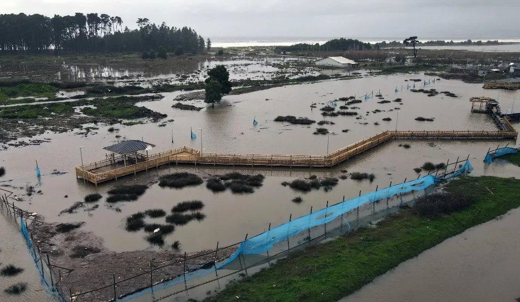 Félmillió ember maradt áram nélkül a Chilén végigsöprő viharok miattThis aerial view shows a flooded area in the coastal city of Arauco, BioBio region, province of Arauco, Chile on July 16, 2026, following strong storms hitting the region. Three people died and 76 were affected amid a storm with heavy rains, swells, and winds that is impacting 10 of the countrys 16 regions, the government reported. (Photo by GUILLERMO SALGADO / AFP)