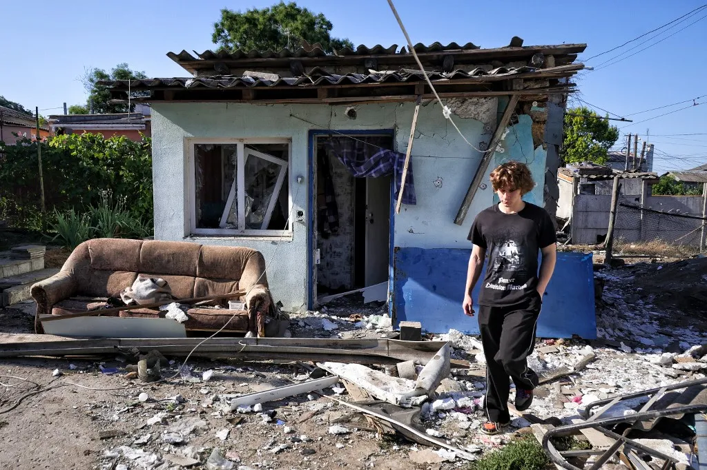 A young man walks past a building damaged in a drone strike in Odesa, Ukraine, on July 6, 2026. Residential buildings were damaged in the city's Kyivskyi district, and a garage cooperative was hit in the Khadzhybeiskyi district. At least one person is reported injured. (Photo by Nina Liashonok/Ukrinform/NurPhoto) (Photo by Nina Liashonok / NurPhoto via AFP)