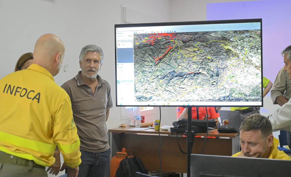 Spain's Interior Minister Fernando Grande-Marlaska listens to a member of the Infoca (Andalusia Wildfire Service) as he visits the advanced command post of the Los Gallardos fire in Turre, in Almeria Province, on July 10, 2026 in the aftermath of a wildfire that killed 12. Twelve people were killed and 23 are missing after a fast-moving wildfire tearing through area in southern Spain, home to many foreign residents. Spain has been sweltering in extreme heat, creating tinderbox conditions favourable for the rapid spread of wildfires. (Photo by Jose JORDAN / AFP)