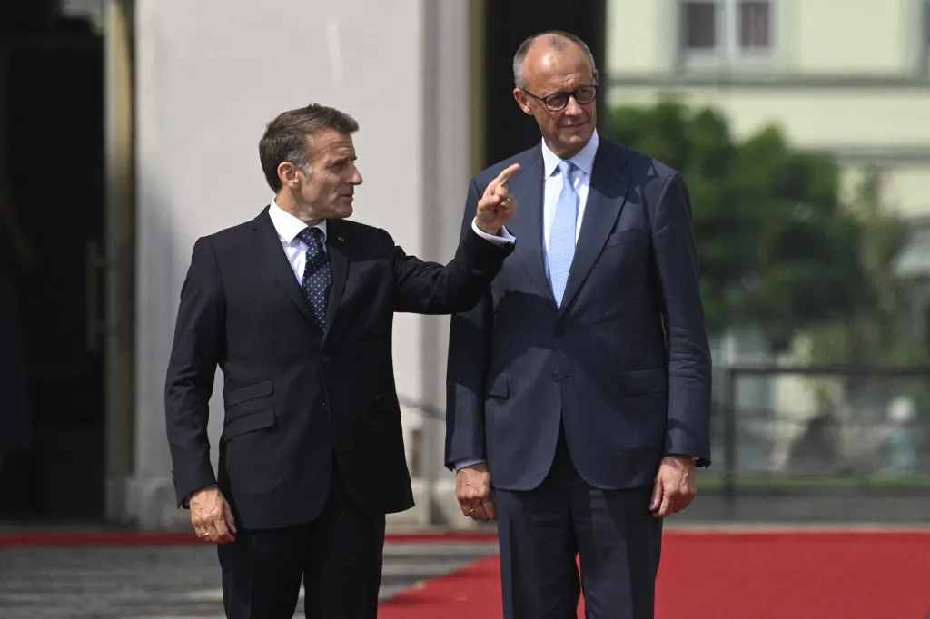 German Chancellor Friedrich Merz and France's President Emmanuel Macron stand in front of the Augustusburg castle as they arrive to review a military guard of honor in Bruehl, western Germany, on July 17, 2026, where they will attend a plenary session of the 26th German-French cabinet. (Photo by INA FASSBENDER / AFP), francia–német védelmi együttműködés