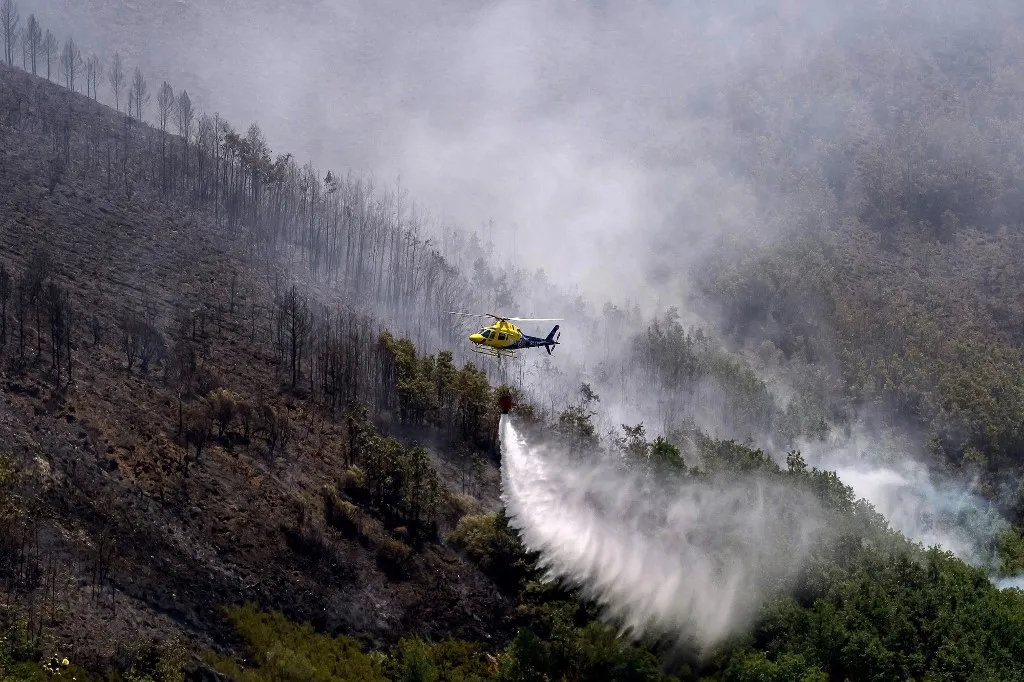 LEON, SPAIN - JULY 08: A helicopter drops water over a wildfire that broke out the previous day in Espina de Tremor, reached level 1 on the Potential Severity Index (IGR-1) and threatened more than 30 hectares of forested land in Leon, Spain, on July 8, 2026. Samuel de Roman / Anadolu (Photo by Samuel de Roman / Anadolu via AFP), spanyolországi erdőtűz