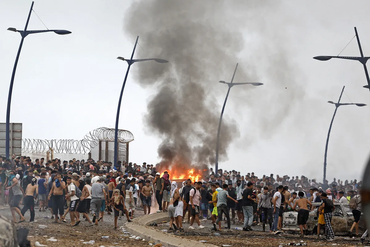 People gather at the site of clashes near Fnideq, on the Morocco-Spain border, on July 31, 2026. Thousands of migrants crossed overnight from Morocco into Spain's north Africa's Ceuta enclave, a police source said on July 31, adding that it was impossible to estimate how many people in total. A total of 18 people died while attempting to reach the Spanish enclave, the source said. (Photo by Abdel Majid BZIOUAT / AFP)