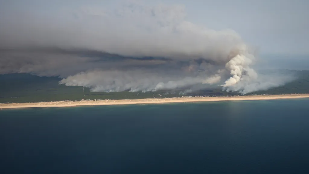 This aerial photograph shows smoke emanating from the wildfire north of the Arcachon basin covering the forest, with a view of a beach and the Atlantic Ocean (bottom) near Lege-Cap-Ferret, southwestern France, on July 24, 2026. France has been battered by