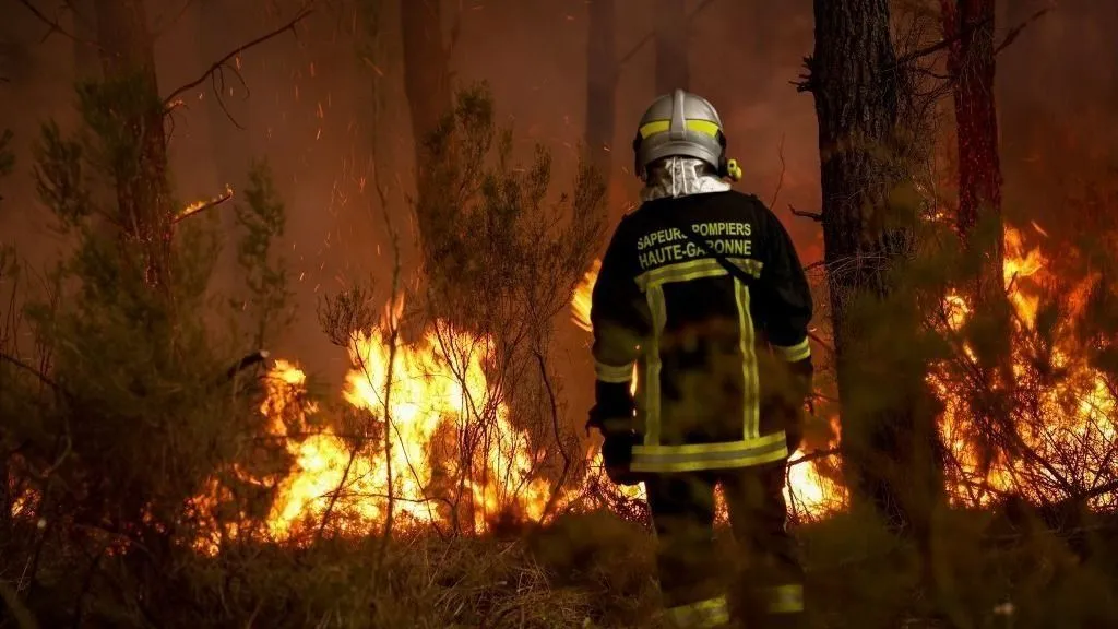 Erdőtűz pusztít Spanyolországban, magyar nő számolt be a pokoli napokról, A firefighter stands before flames as a forest fire rages in Saint-Jean-d'Illac, some 30km from Bordeaux, on July 26, 2026 as a wildfire has been ravaging the forest north of the Arcachon Basin (Gironde). The 220,000 people evacuated due to the massive wildfire in France's Gironde region will not be able to return home "until the fire has been brought under control", the local prefect said, also ruling out any normal workday on Monday in the affected towns, ahead of a possible worsening of the situation on Tuesday due to an expected rise in temperatures. (Photo by ROMAIN PERROCHEAU / AFP)