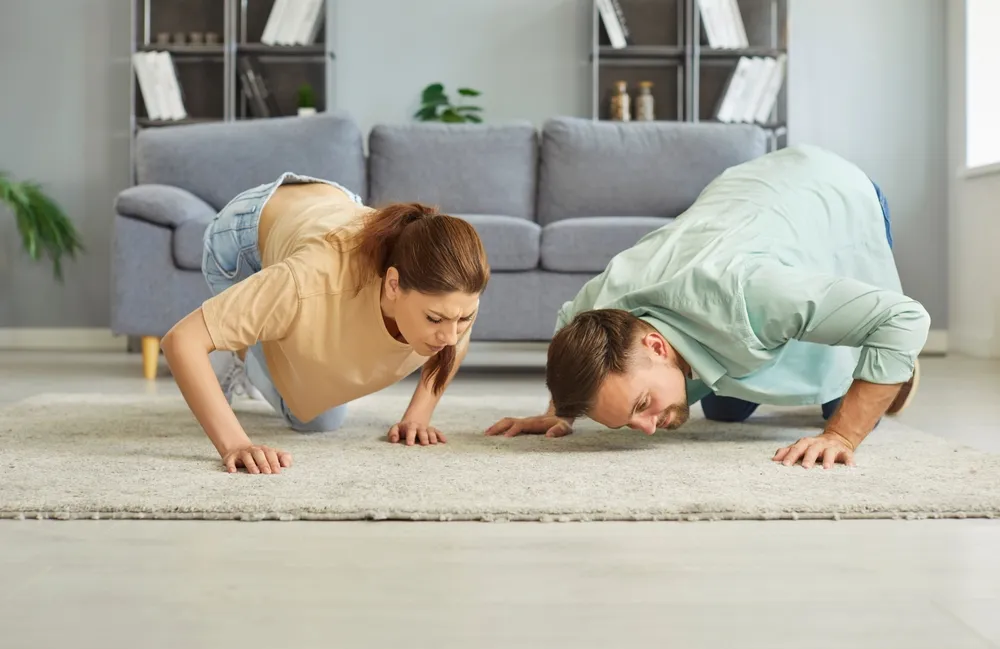 Régi szőnyeg újbóli puhaságát ellenőrző fiatal pár a szőnyeg tisztítása után