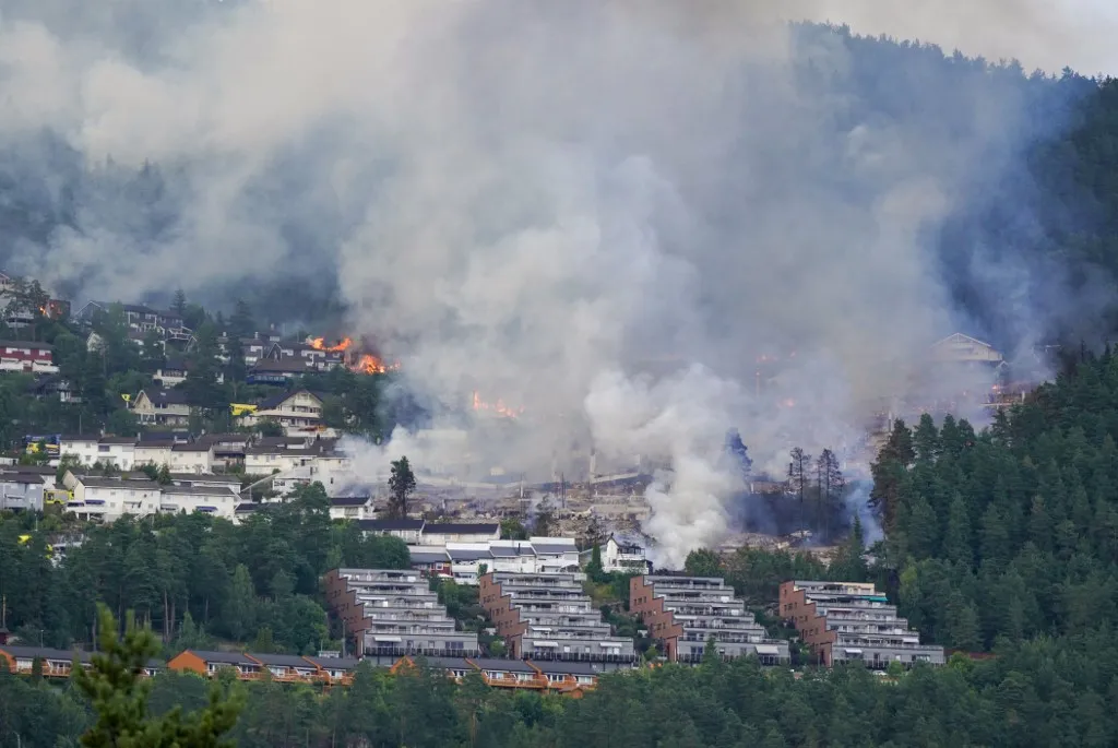 Az erdőtűz több mint száz lakóházat pusztított el a dél-norvégiai Drammen térségében An overview shows smoke rising from a large fire that has spread from terraced houses by Krokstadelva in Drammen, south-west of Oslo, Norway, on July 17, 2026. (Photo by Thomas Fure / NTB / AFP) / Norway OUT
