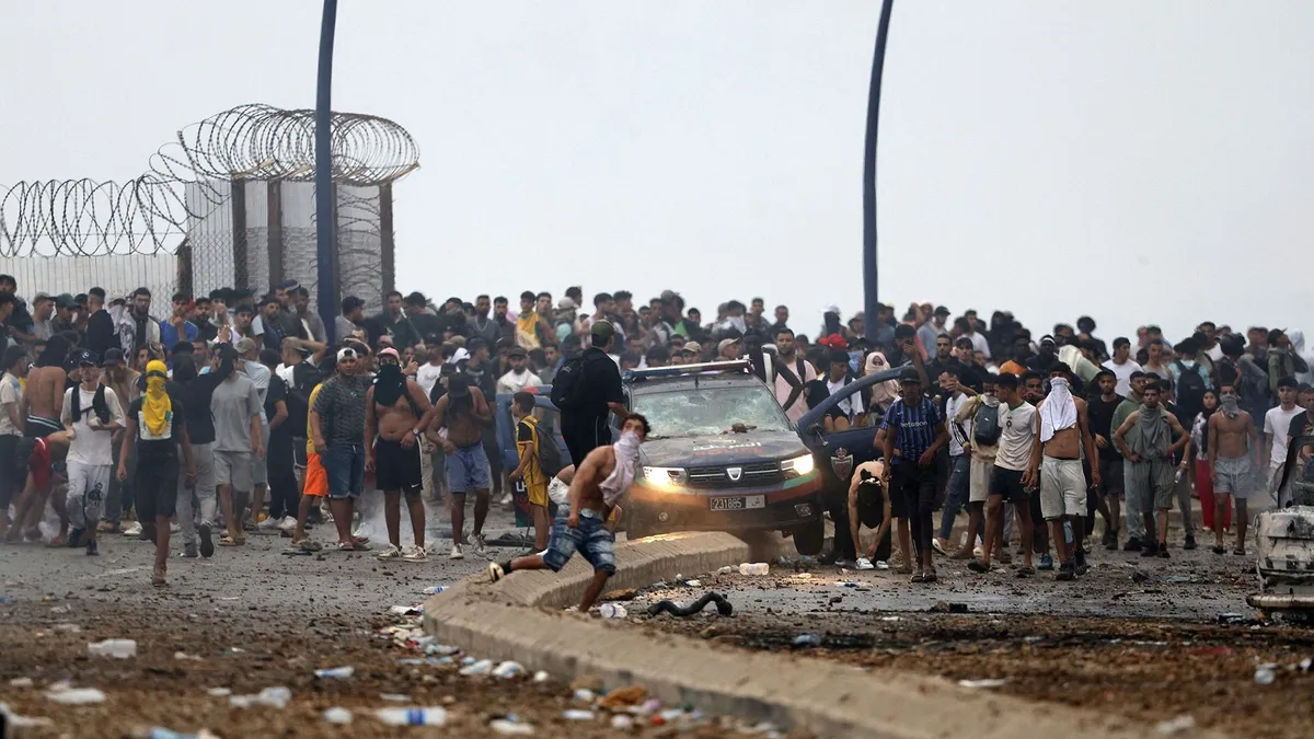 People gather at the site of clashes near Fnideq, on the Morocco-Spain border, on July 31, 2026. Thousands of migrants crossed overnight from Morocco into Spain's north Africa's Ceuta enclave, a police source said on July 31, as Prime Minister Pedro Sanchez was set to arrive to manage the latest migrant crisis on the border. (Photo by Abdel Majid BZIOUAT / AFP)