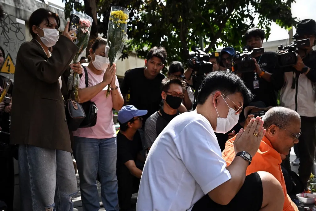 Gyúlékony dekoráció miatt vizsgálják a bangkoki bártüzet (A képen gyászolók) , Relatives of a victim of a bar fire pray in front of the Rong Beer Na Lat Phrao bar in Bangkok on July 14, 2026. Grieving relatives of the victims of a huge Bangkok bar fire claimed their bodies on July 14 as the death toll rose to 30, even as others held out hope that missing loved ones were alive. (Photo by Lillian SUWANRUMPHA / AFP)