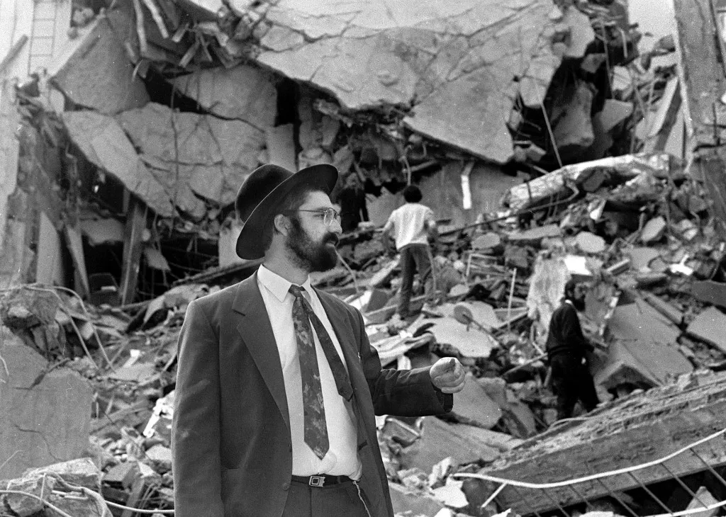 (FILE) A man walks over the rubble left after a bomb exploded at the Argentinian Israeli Mutual Association (AMIA in Spanish) in Buenos Aires, 18 July 1994. As arguments for the AMIA trail begin, 13 January 2004, the Active Memory association, formed by the victims' relatives of the 1994 attack, will hold the Argentine government responsible for it and also seek life imprisonment for just one of the accused - Carlos Telleldin.          AFP PHOTO/ALI BURAFI (Photo by Ali BURAFI / AFP)